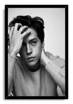Cole Sprouse framed wall art print displays a black-and-white pensive portrait of the actor in a textured sweater within a black frame.