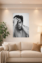 Cole Sprouse in a bright living room above a beige sofa.