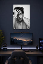 Cole Sprouse in a gaming desk setup above a monitor.