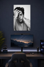Cole Sprouse in a gaming desk setup above a monitor.