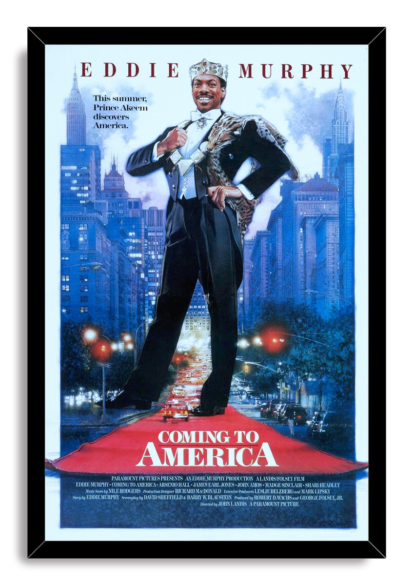 Coming to America framed wall art print featuring Eddie Murphy as Prince Akeem, standing over a red carpet amid a blue city skyline.