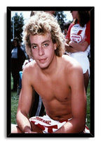 Corey Haim framed wall art print presents the shirtless curly blond actor seated outdoors in a black mitered frame.