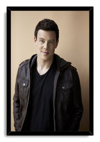 Cory Monteith framed wall art print with a black border, portraying him in a dark jacket against a warm beige background.