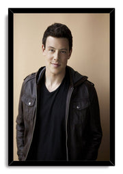 Cory Monteith framed wall art print with a black border, portraying him in a dark jacket against a warm beige background.