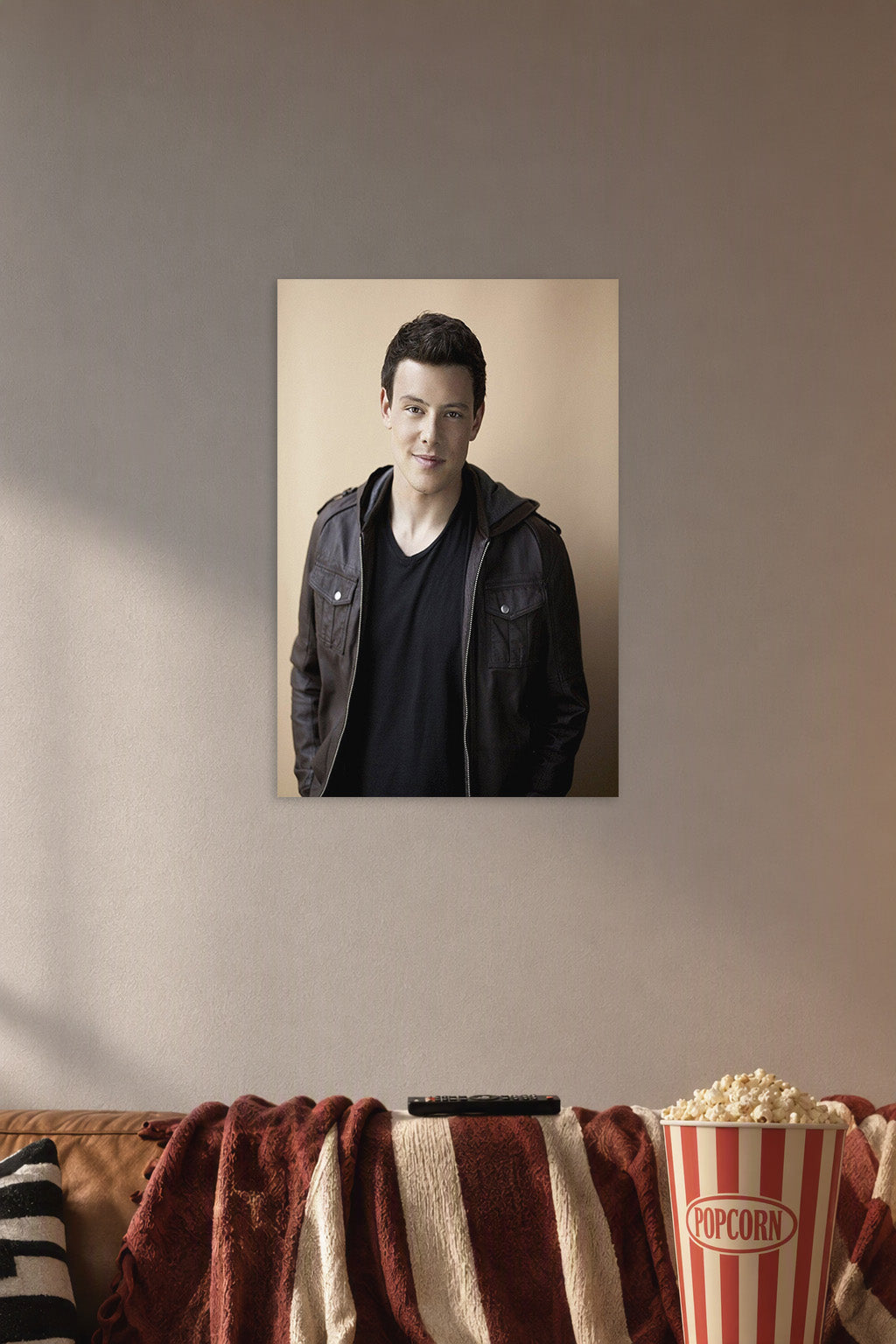 Cory Monteith in a cozy movie room above a brown sofa with popcorn.