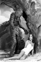 Creature From the Black Lagoon poster depicts the Gill-man reaching toward a startled woman in a white swimsuit beneath a rocky arch.