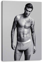 David Beckham canvas wall art print presents a monochrome portrait of the tattooed man standing in gray boxer briefs.