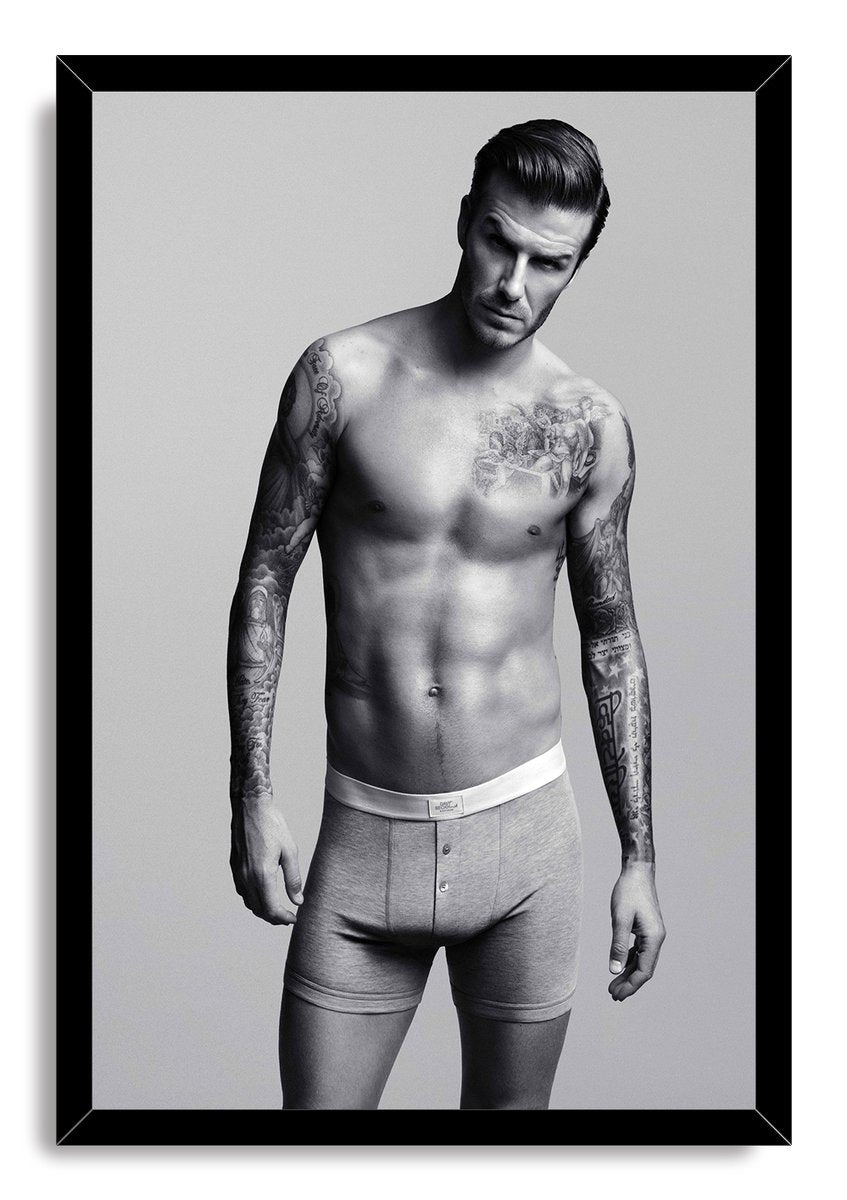David Beckham framed wall art print features a black frame around a monochrome portrait of the tattooed man in boxer briefs.