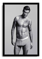 David Beckham framed wall art print features a black frame around a monochrome portrait of the tattooed man in boxer briefs.