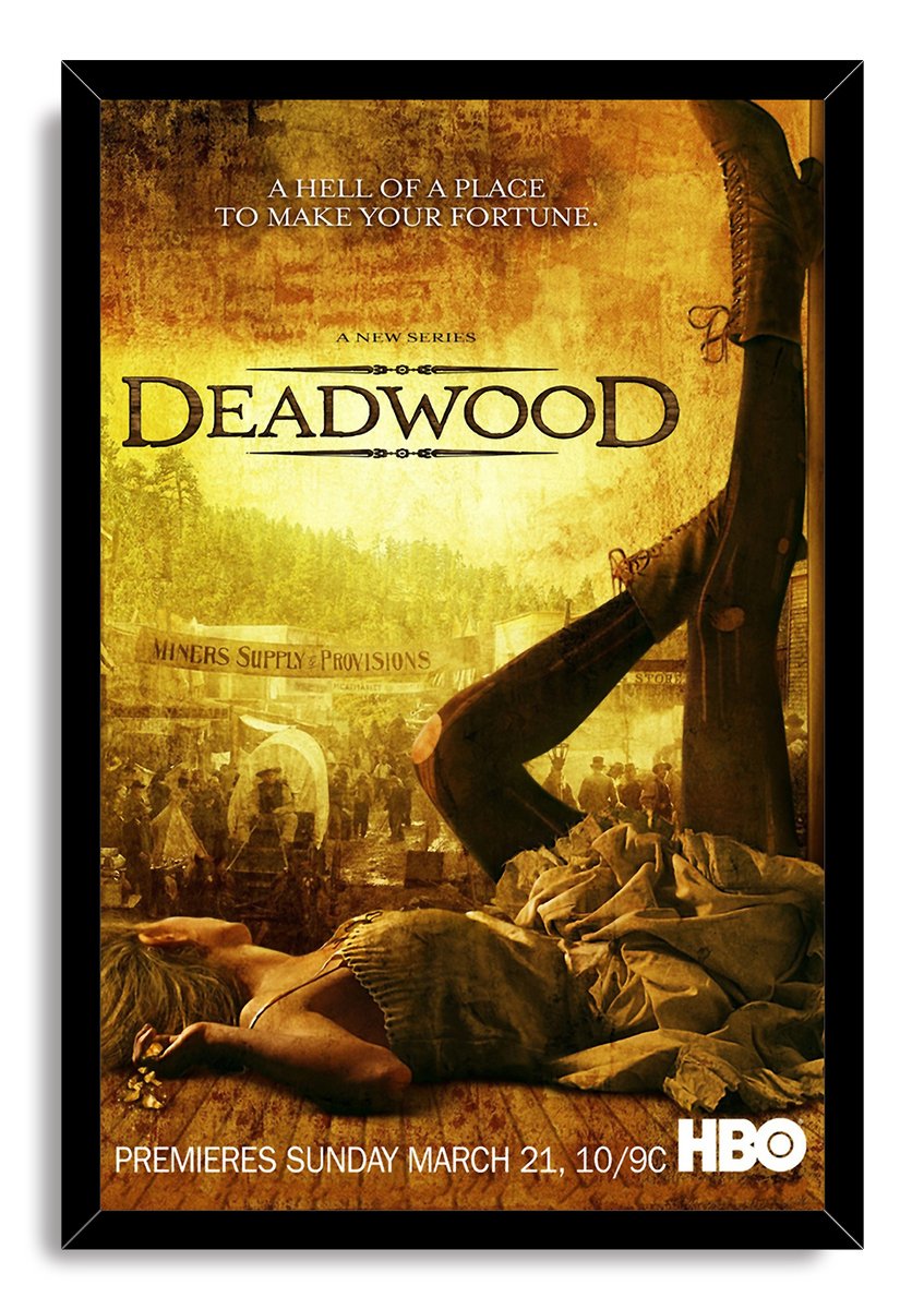 Deadwood framed wall art print in a black frame, featuring a sepia frontier street, fallen woman, raised boots, and HBO text.