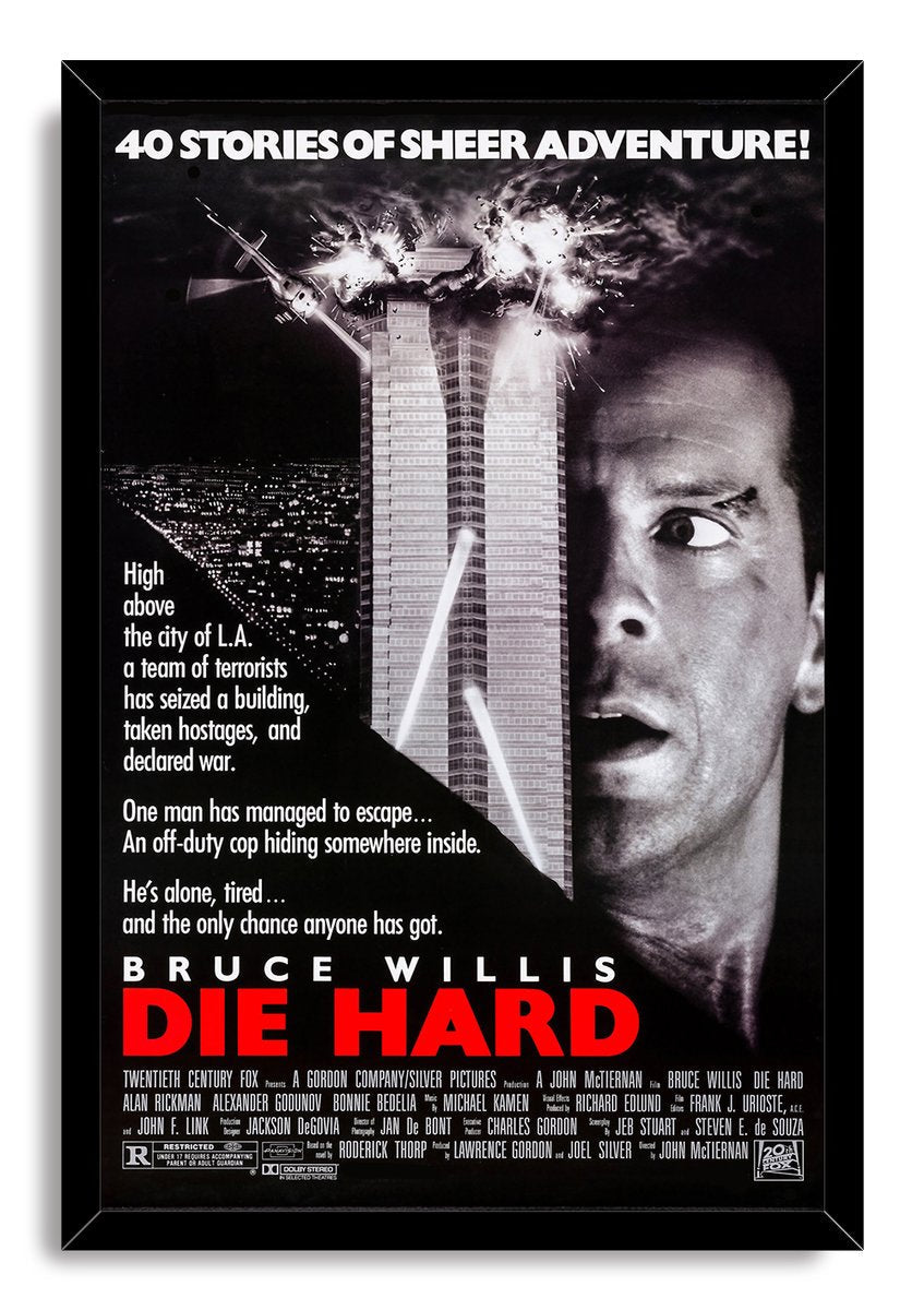 Die Hard framed wall art print presents Bruce Willis beside an exploding skyscraper, with white typography and a bold red title.