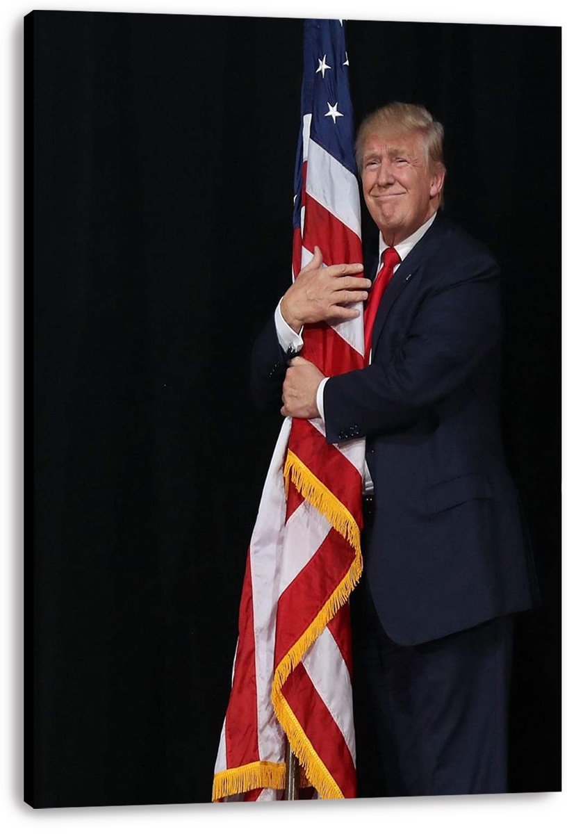 Donald Trump canvas wall art print displays him smiling as he embraces a red, white, and blue American flag on black.