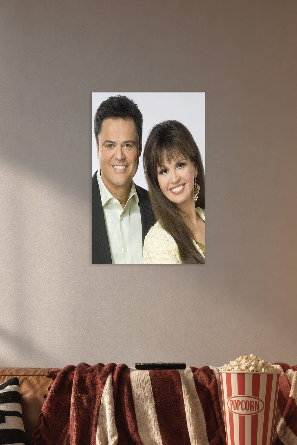 Donny & Marie Osmond in a cozy movie room above a brown sofa with popcorn.