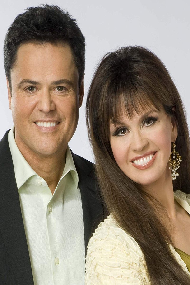 Donny and Marie Osmond poster portrait with the smiling duo in formal black, cream, and white attire against gray.