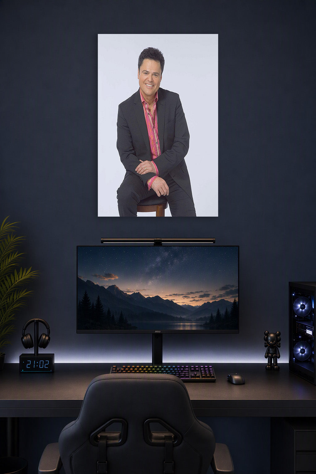 Donny Osmond in a gaming desk setup above a monitor.