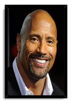 Dwayne The Rock Johnson framed wall art print displays his warm smiling portrait in a black frame, wearing a dark jacket and white shirt.