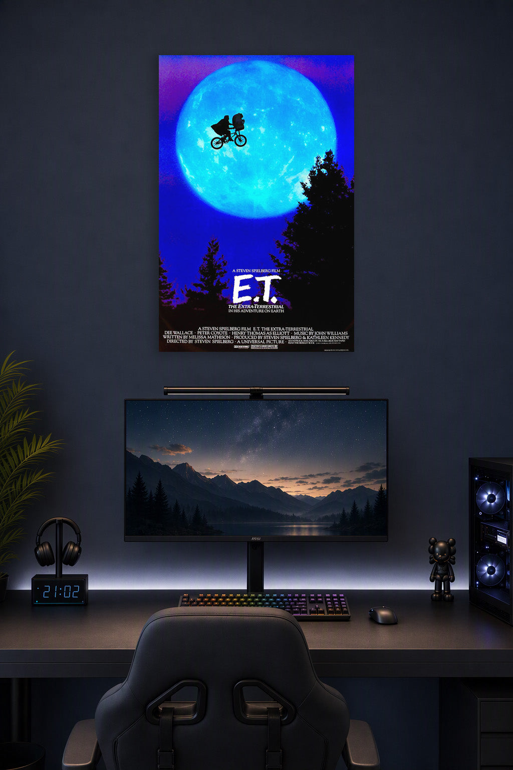 E.T. The Extra-Terrestrial in a gaming desk setup above a monitor.
