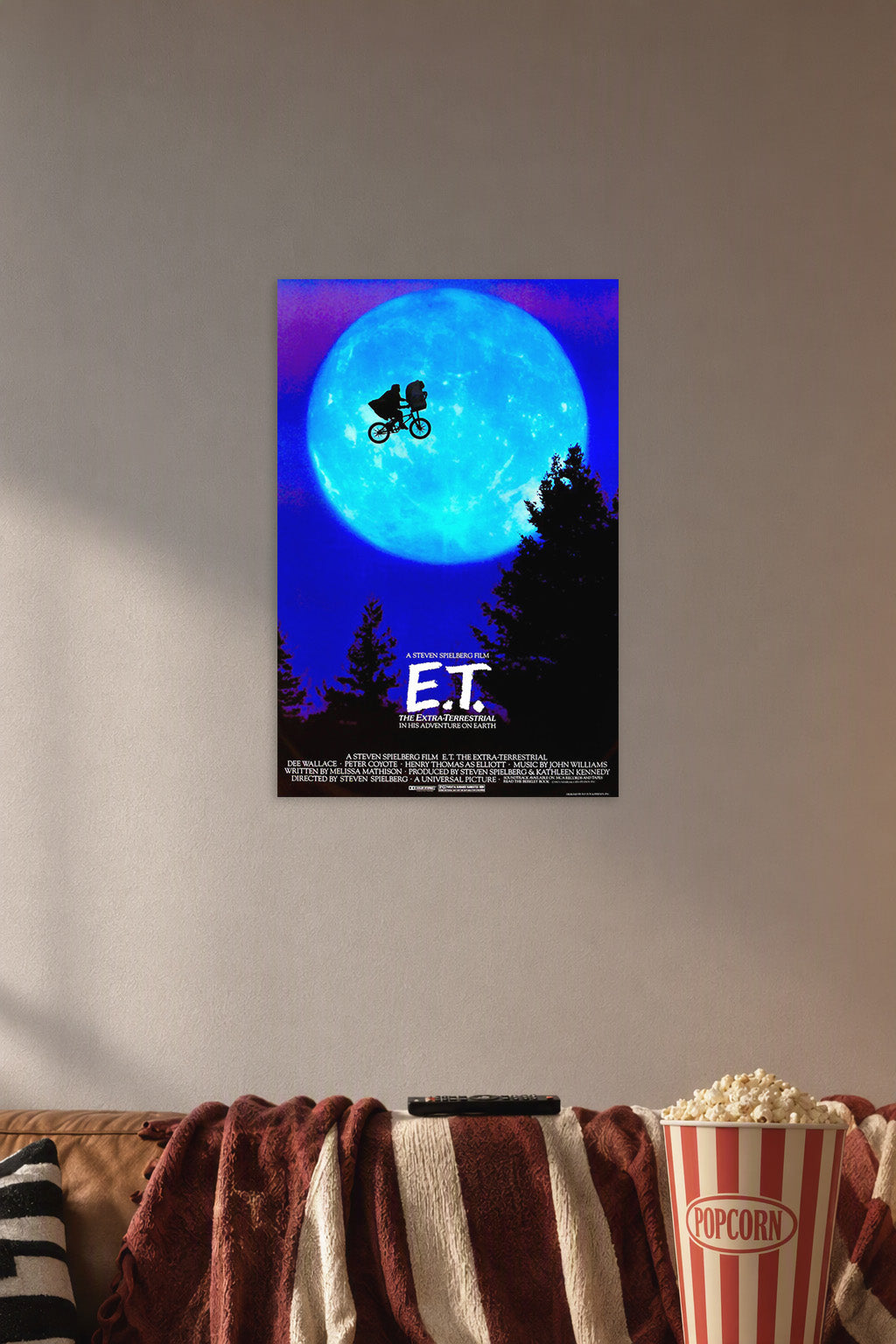 E.T. The Extra-Terrestrial in a cozy movie room above a brown sofa with popcorn.