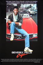Beverly Hills Cop poster featuring Eddie Murphy seated on a red Mercedes with a pistol, city traffic, and black title border.
