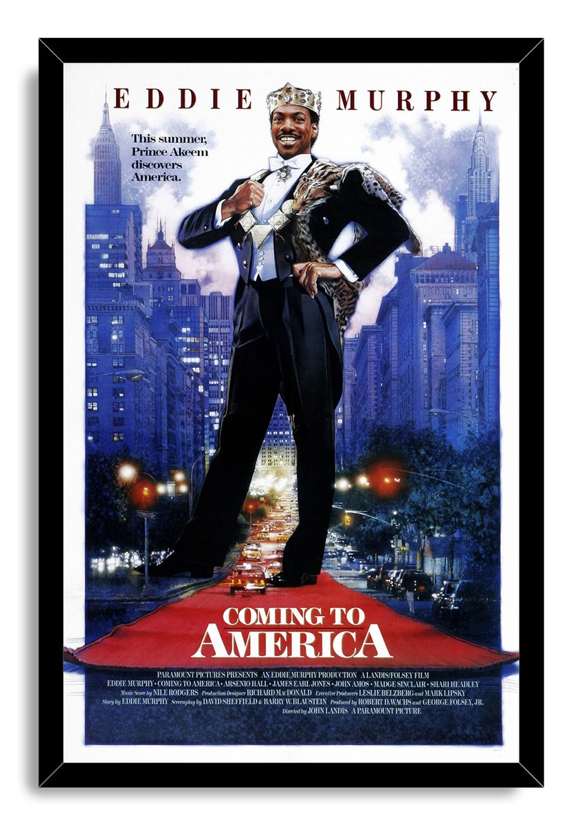 Framed Coming to America wall art print with Eddie Murphy as Prince Akeem, city towers, glowing traffic, and red title text.