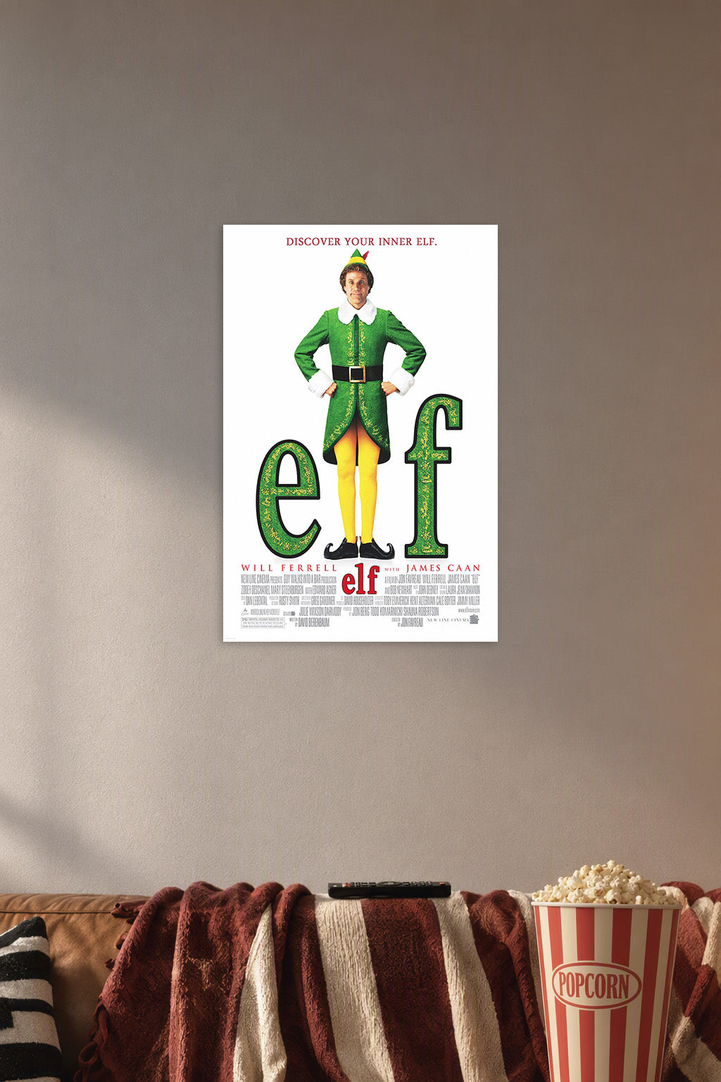 Elf Movie Poster in a cozy movie room above a brown sofa with popcorn.