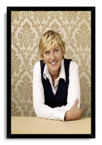 Ellen DeGeneres framed wall art print in a black border, portraying her smiling with folded arms against tan patterned wallpaper.