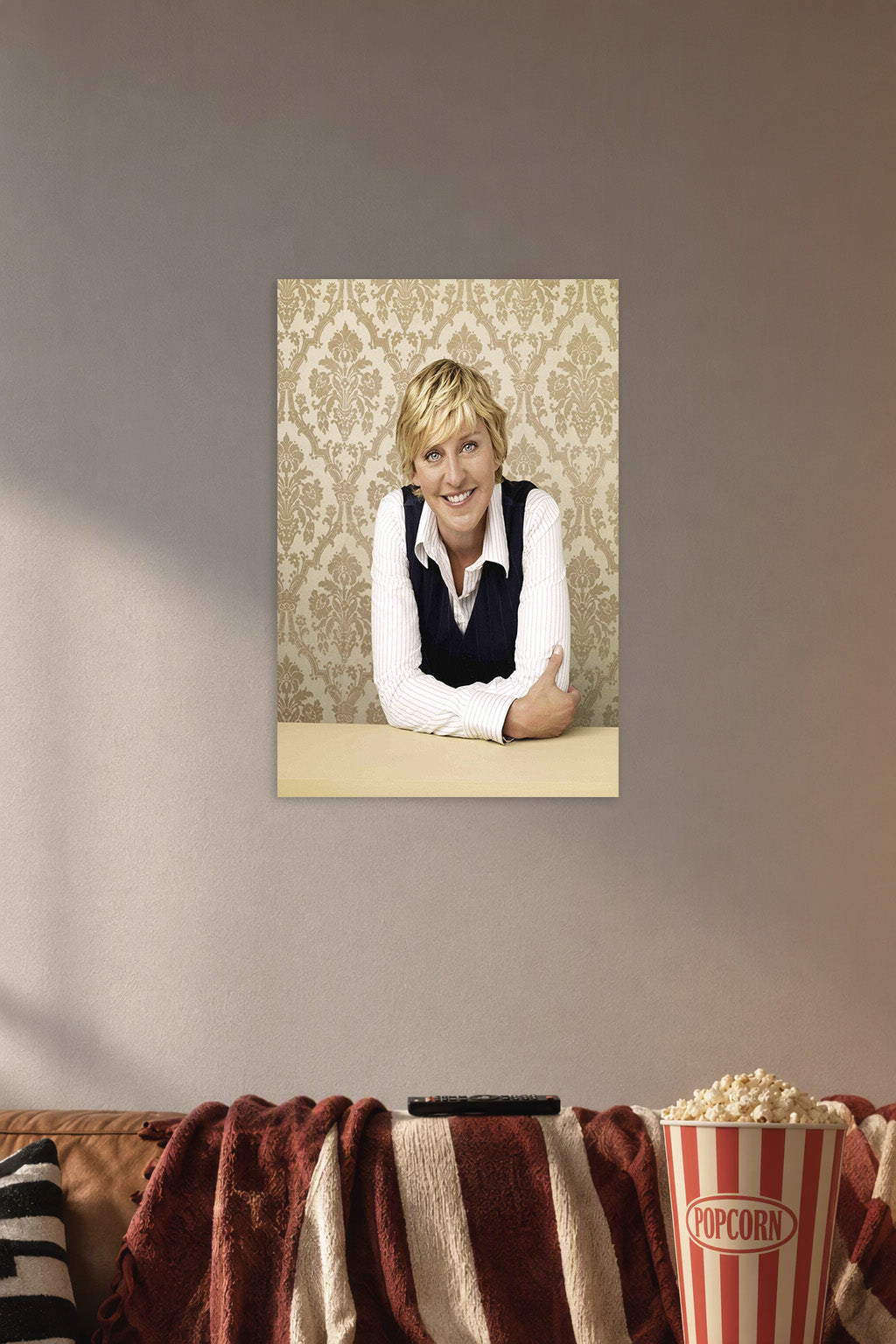 Ellen DeGeneres in a cozy movie room above a brown sofa with popcorn.