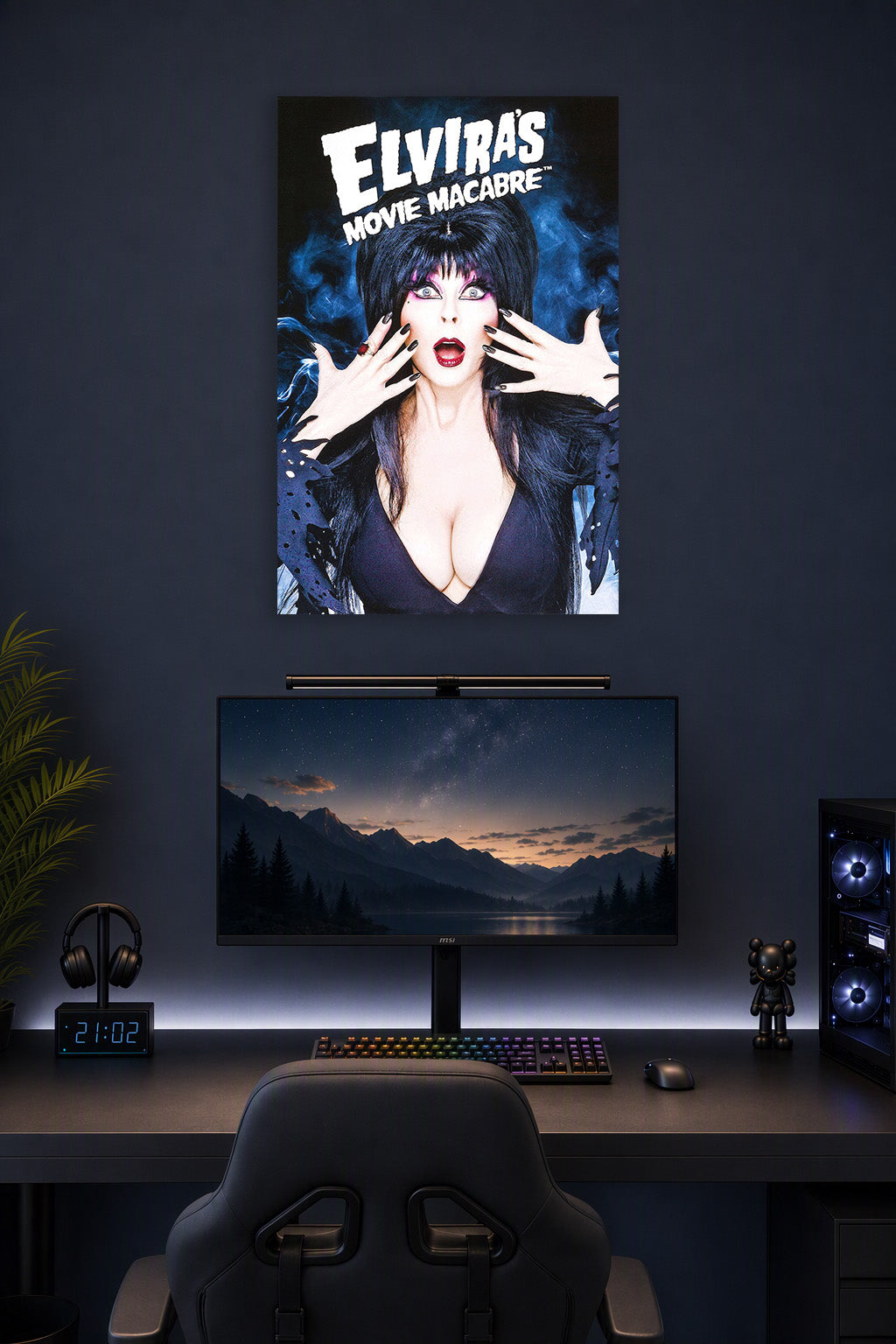 Elvira Mistress of the Dark in a gaming desk setup above a monitor.