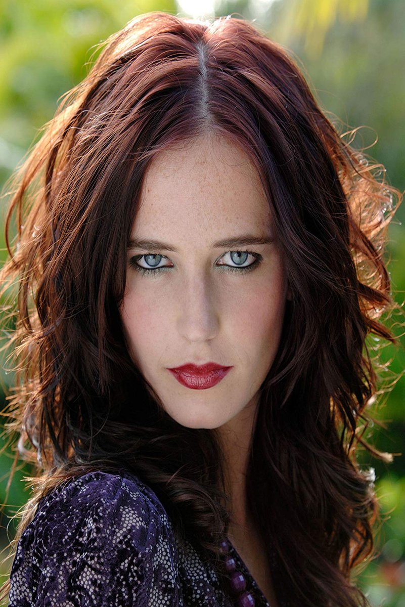 Eva Green poster presents a close-up outdoor portrait with auburn wavy hair, pale blue eyes, red lipstick, and a green blurred background.