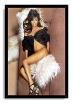 Eva Longoria framed wall art print portraying the actress reclining on a tan sofa with white fur throws and a black outfit.