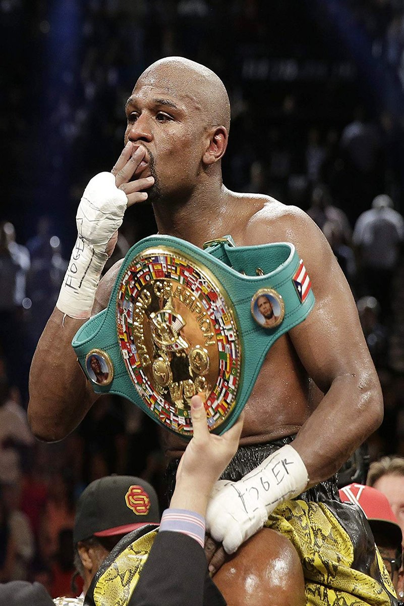 Floyd Mayweather wall art print captures the boxer kissing his fingers while wearing a green and gold championship belt in a crowded arena.