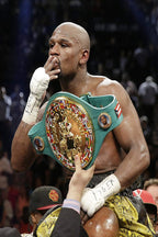 Floyd Mayweather wall art print captures the boxer kissing his fingers while wearing a green and gold championship belt in a crowded arena.