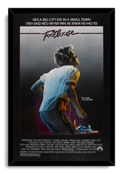 Footloose movie poster wall art print in a black frame, featuring a headphone-wearing young man and small town skyline.