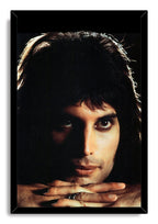 Freddie Mercury framed wall art print presents a dark close-up portrait with warm-lit face, folded hands, and black frame.