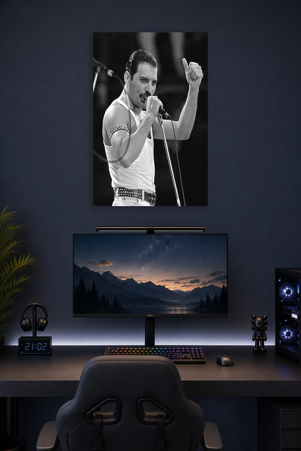 Freddie Mercury in a gaming desk setup above a monitor.