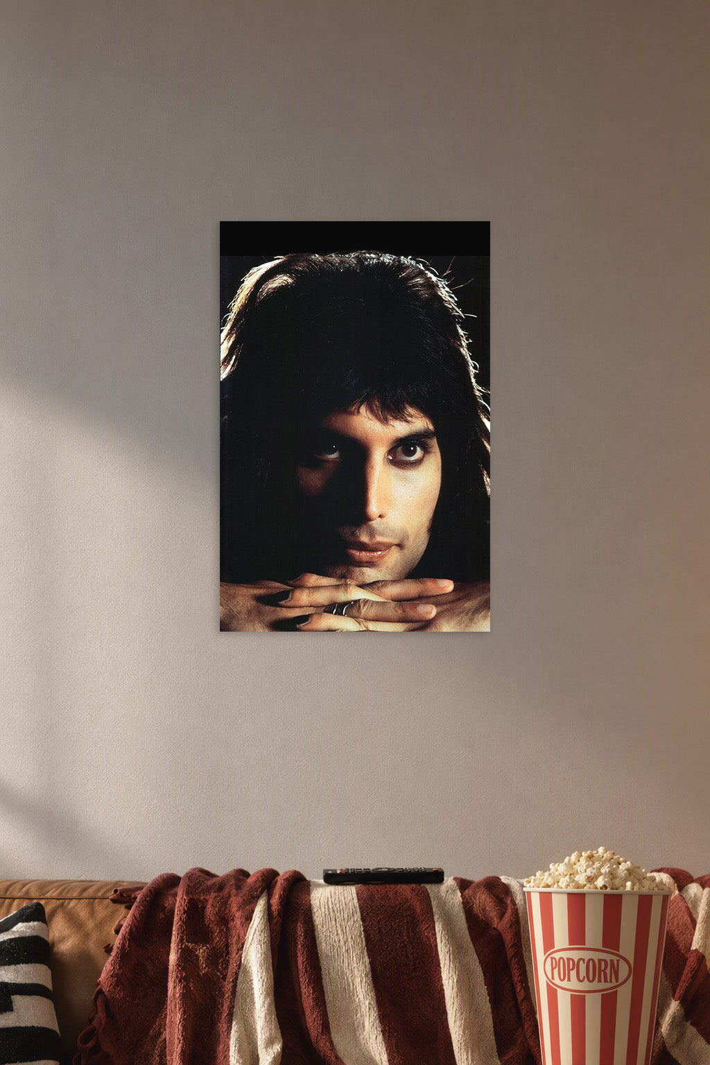 Freddie Mercury in a cozy movie room above a brown sofa with popcorn.
