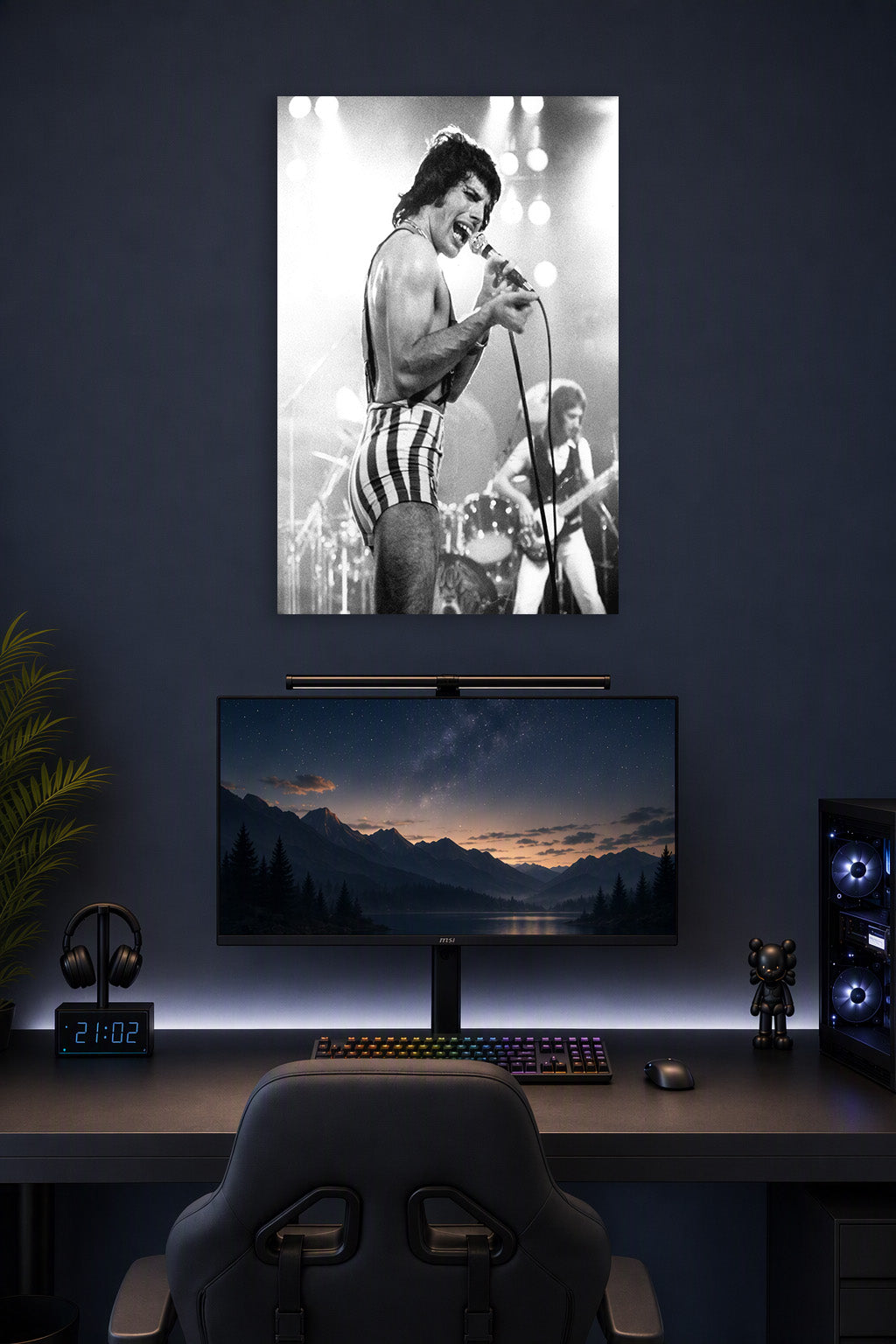 Freddie Mercury in a gaming desk setup above a monitor.