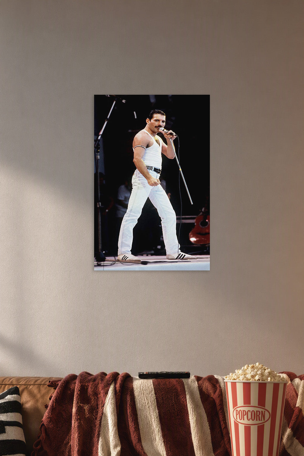 Freddie Mercury in a cozy movie room above a brown sofa with popcorn.