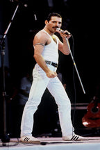Freddie Mercury wall art print captures the singer on a dark stage in a white tank top and trousers, gripping a microphone.