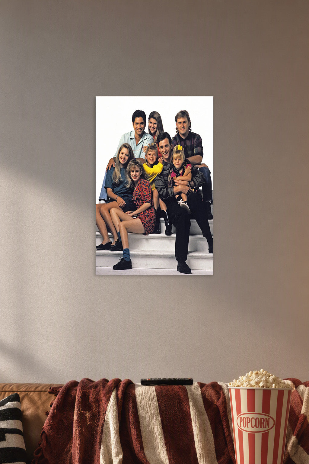 Full House Cast Family in a cozy movie room above a brown sofa with popcorn.