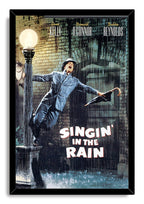 Singin' in the Rain framed wall art print of Gene Kelly dancing in rainfall beside a streetlamp, bordered by a black frame.