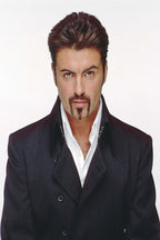 George Michael poster features a direct portrait in a dark double-breasted coat and open white shirt against white.