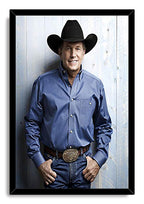 George Strait framed wall art print in a black frame, with the singer in western attire posed before a light wooden wall.