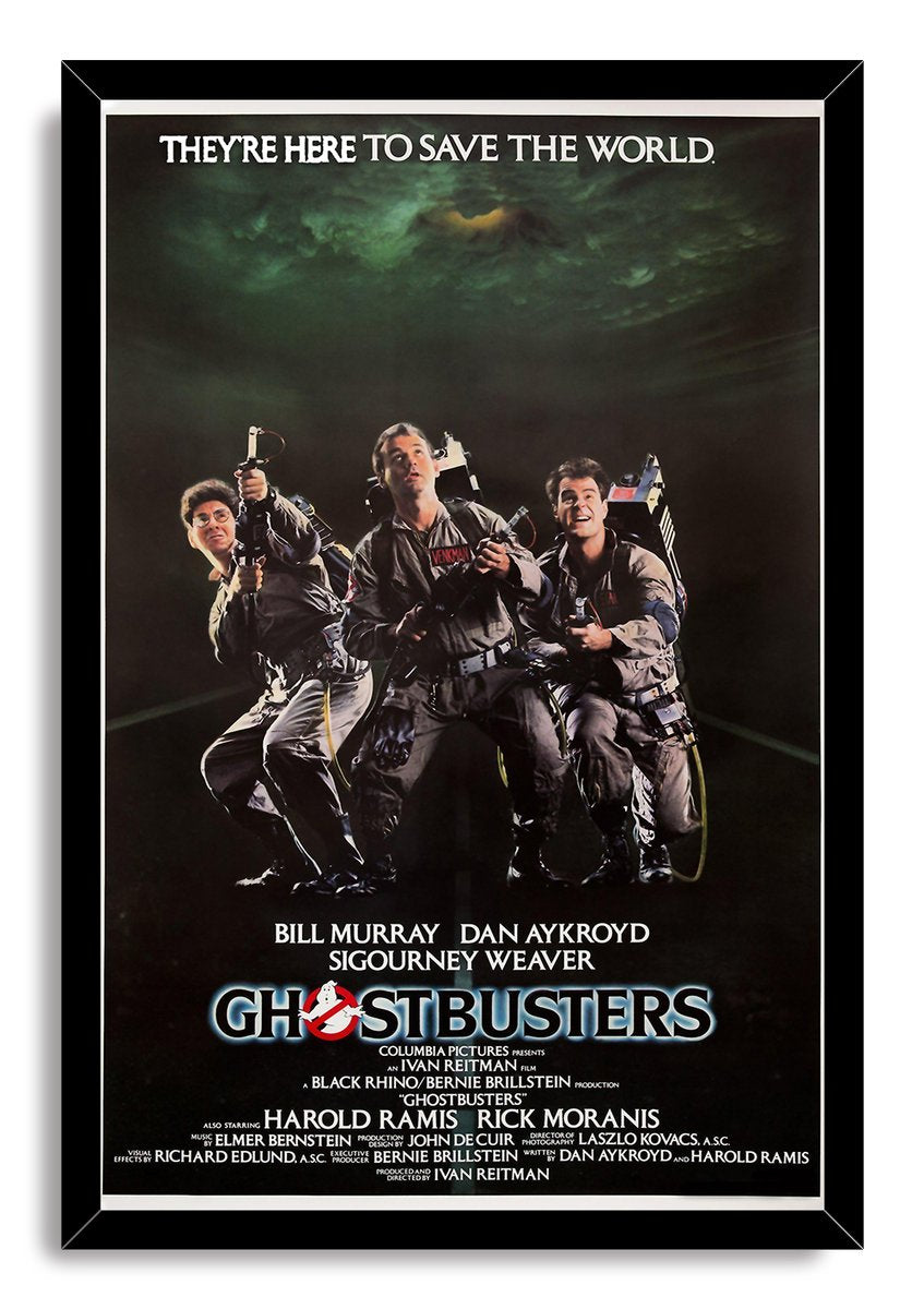 Ghostbusters framed wall art print in a black frame, featuring three proton-pack-equipped men beneath dark green clouds.