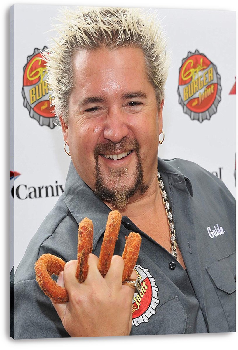 Guy Fieri canvas wall art print presents the smiling chef in a gray shirt, holding fried snacks against a branded event backdrop.