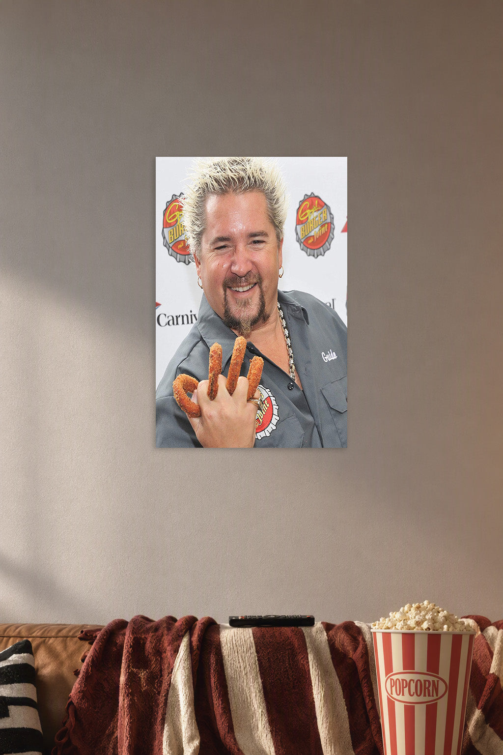 Guy Fieri in a cozy movie room above a brown sofa with popcorn.