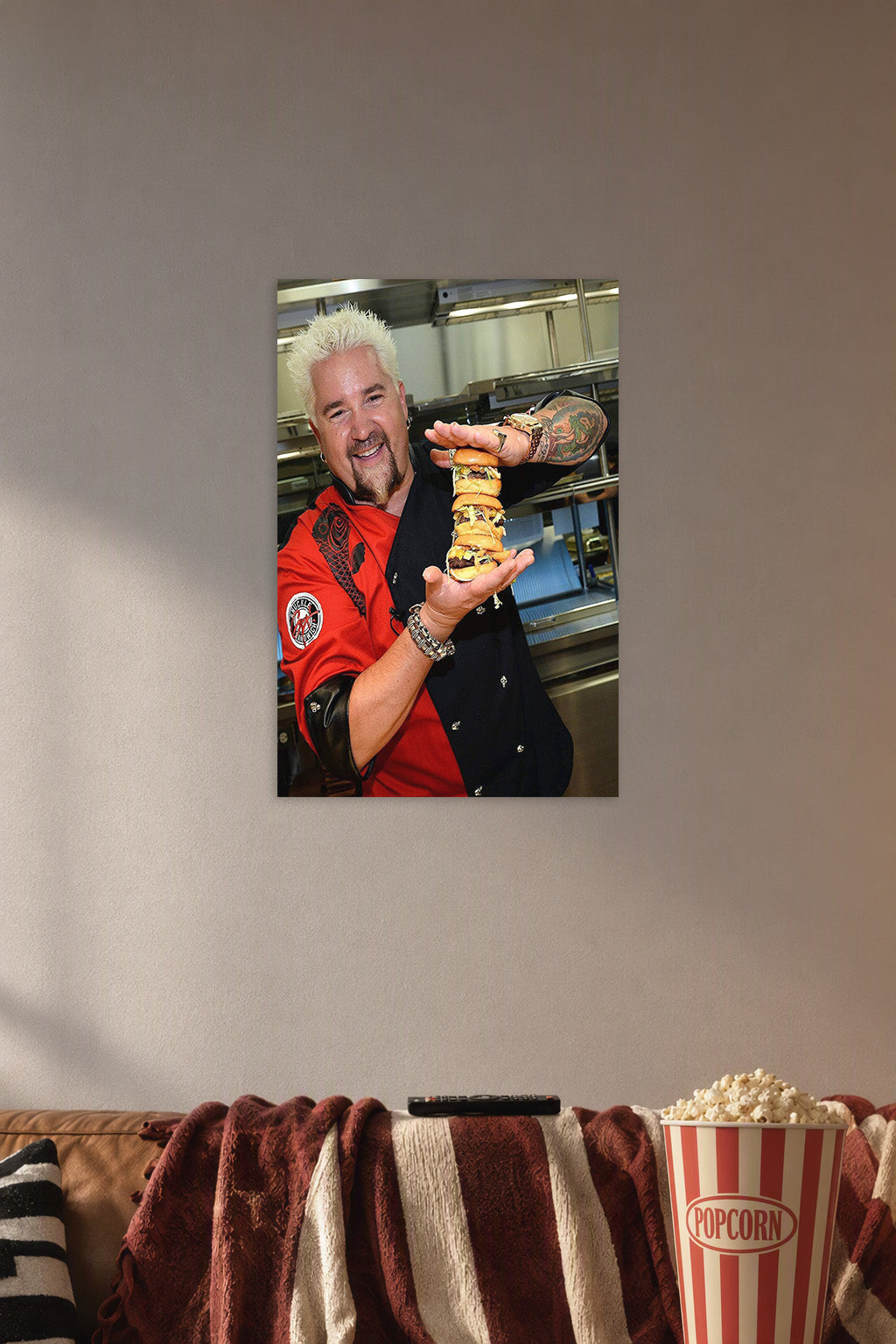 Guy Fieri in a cozy movie room above a brown sofa with popcorn.
