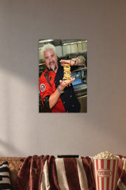 Guy Fieri in a cozy movie room above a brown sofa with popcorn.