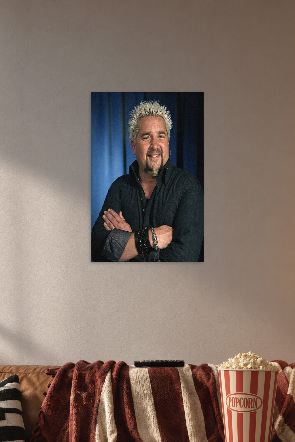 Guy Fieri in a cozy movie room above a brown sofa with popcorn.