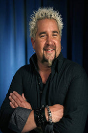 Guy Fieri wall art print features a smiling portrait with spiky blond hair, crossed arms, black shirt, and blue backdrop.
